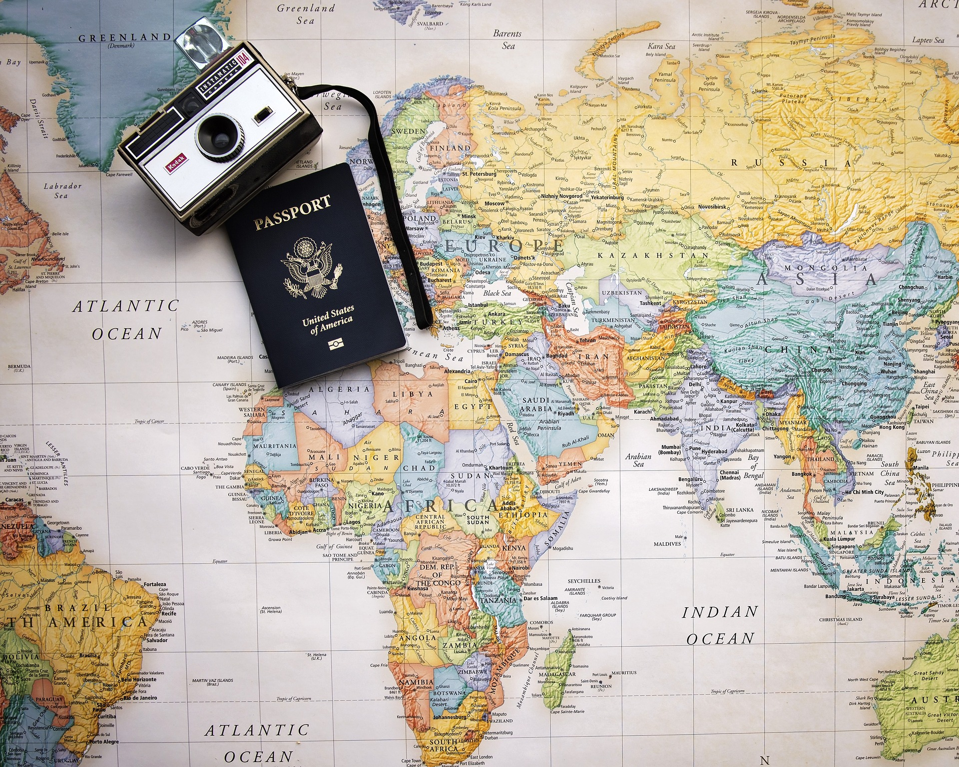 A passport and camera placed on a world map shown on SelfishMe Travel LLC